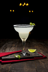Classic Margarita Cocktail with lime and ice on wooden background.
