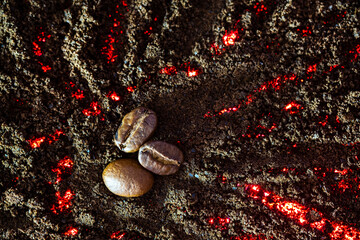 Close-up of roasted coffee beans on ground coffee with fire elements in ground coffee texture....