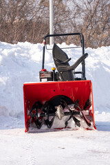 Snowplow against the background of snowdrifts. Portable snowplow in the yard.