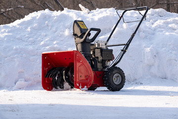 Snowplow against the background of snowdrifts. Portable snowplow in the yard.