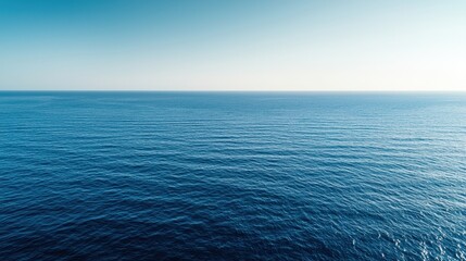 Fototapeta premium A serene view of a calm ocean under a clear blue sky, showcasing the vastness of water and horizon blending seamlessly.