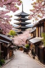 Cherry blossoms in Kyoto with historic pagoda and traditional houses along a scenic street, perfect for travel and cultural photography.