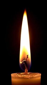 Una vela ardiendo sobre un fondo negro en un video vertical