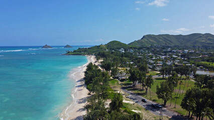 Aerial view of Hawaiian coastline with turquoise water, sandy beach, and lush green mountains.