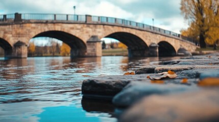 Fototapeta premium A medieval stone bridge gracefully spans a calm river, with weathered stones and peaceful water mirroring the beauty of nature and history