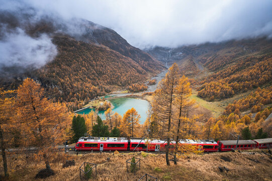 Scenic view of red train from Rhaetian Railway with Alp Grum Lake, Graubunden. Switzerland.