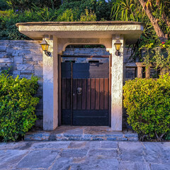The external main entrance wooden door and the garden of a luxury classic design family house. Travel to Athens, Greece.