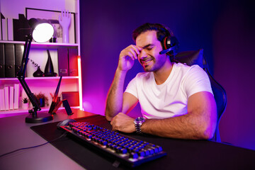 Serious face gaming streamer concentrating gaming players trying to pass at mission completed, using headset and mic for communicate others on streaming live at neon lighting studio room. Surmise.