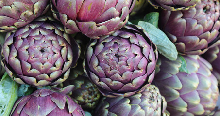 Background of ripe green artichokes for sale at the market called MAMME in Italian