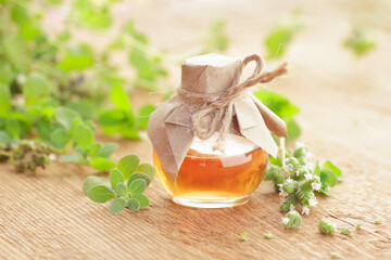 Oregano oil or extract  on wooden background with fresh leaves and flowers nearby, copy space, natural medicine,  natural hair and skin treatment, aromatherapy concept