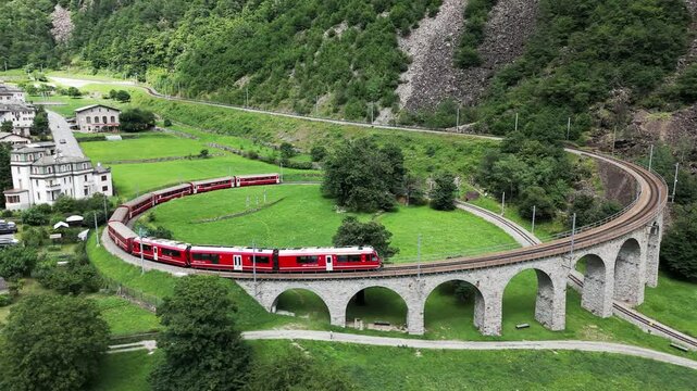 Aerial view of a Bernina Express train crossing the Brusio spiral viaduct of Rhaetian Railway, Grisons canton, Switzerland
