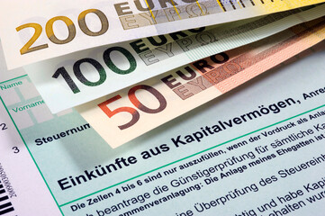 Fototapeta premium Euro Geldscheine liegen auf einem Formular zur Steuererklärung für Einkünfte aus Kapitalvermögen