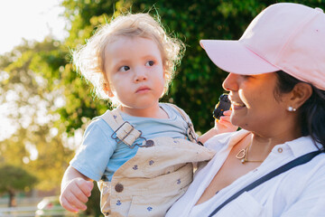 Young latin aunt happily holding her nephew outside at sunset