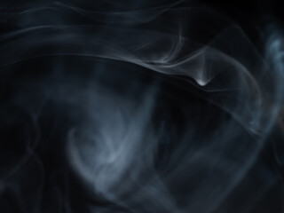 Thick black smoke swirling on black background close up selective focus