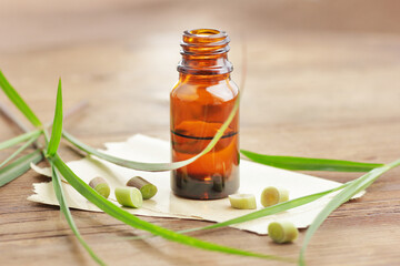 Lemongrass oil or extract  on wooden background with fresh leaves  nearby, copy space, natural medicine, natural hair and skin treatment, aromatherapy concept
