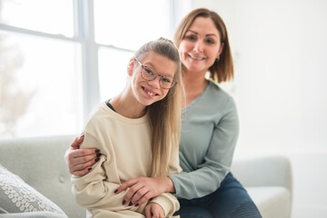 Portrait of disabled girl smiling at camera with her mother at home