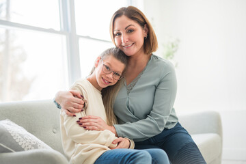 Obraz premium Portrait of disabled girl smiling at camera with her mother at home