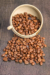Roasted coffee beans spilling from a ceramic cup