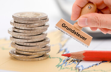 Auf einem finanziellen Diagramm liegt ein Stapel Euromünzen mit Rotstift und ein Stempel mit der...