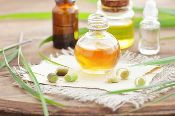 Lemongrass oil or extract  on wooden background with fresh leaves  nearby, copy space, natural medicine, natural hair and skin treatment, aromatherapy concept