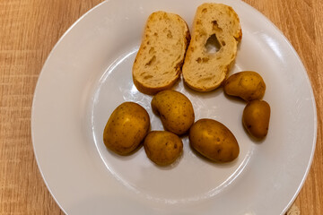 Freshly boiled potatoes and homemade bread on a white plate, ready for a simple meal
