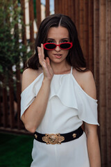 Obraz premium Beautiful fashionable brunette woman in white suit by wooden fence