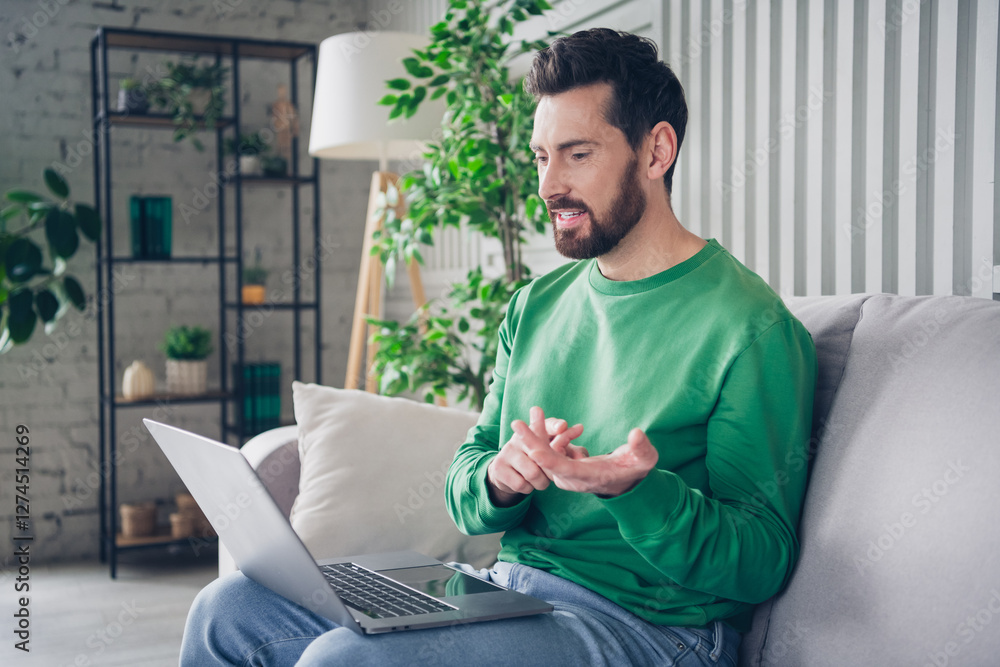 Poster man sitting on a sofa using a laptop during a relaxing day at home