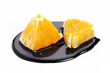 Unique presentation of orange segments with glossy black sauce on white background