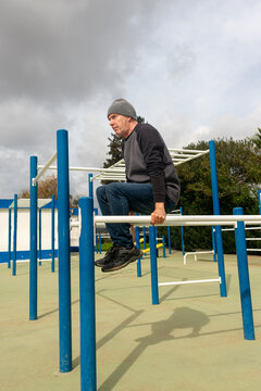 Mature man using an outdoor gym, parallel bars arm exercise
