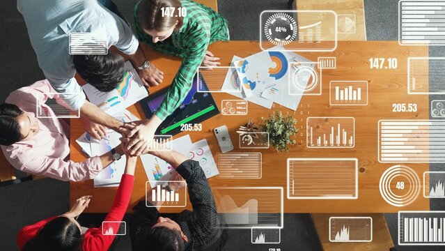Top view of smart team putting hand together at meeting to celebrate successful project or increasing sales. Aerial view of diverse people making stack of hands with investment statistic. Convocation.
