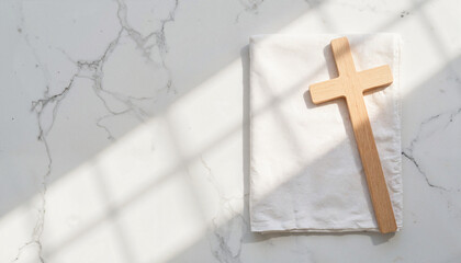 Wooden cross on white cloth against marble background