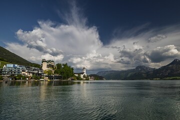 Scenic view of a quaint village by a serene lake surrounded by lush mountains in Austria