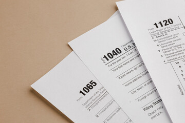 Obraz premium Tax season: Assorted blank white U.S. tax forms including forms 1040, 1065, and 1120, suggesting financial paperwork and tax preparation.