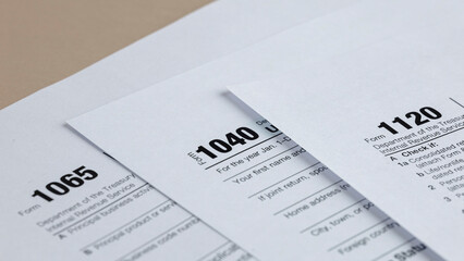 Obraz premium Tax season: various tax forms including 1040, 1065, and 1120 forms representing individual, partnership, and corporate tax obligations.
