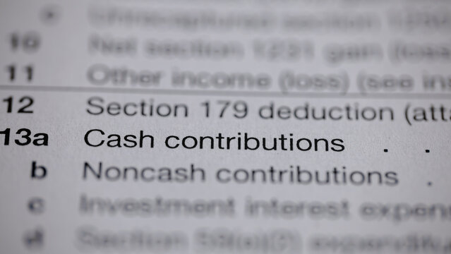 Tax form close-up showcasing donation sections. Itemized cash and noncash contributions highlighted. Financial and tax document.