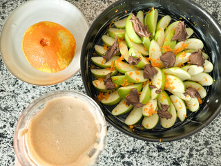 Fruit and chocolate dessert arranged creatively on a marble countertop with an orange