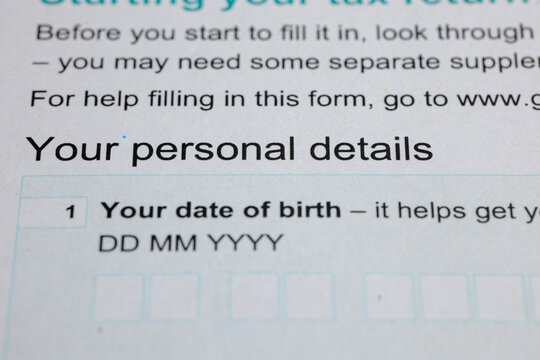 Close-up on a form requiring personal details, specifically date of birth, filled with blanks for Day, Month, and Year; tax-related document snippet