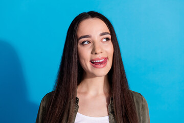 Young woman in casual wear expressing playful emotion against a blue background.