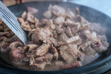 Steaming beef slices simmer in a bubbling broth, releasing rich flavors as they cook. The tender meat absorbs the liquid, creating a delicious dish in progress.
