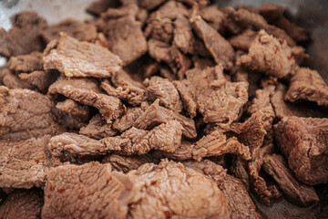 A close-up of cooked beef slices in a pan, showing their texture and slight browning. The meat appears tender and ready for further preparation or serving.