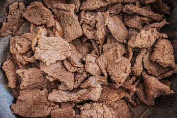 A close-up of cooked beef slices in a pan, showing their texture and slight browning. The meat appears tender and ready for further preparation or serving.