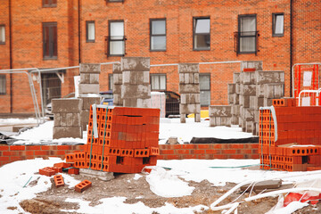 Construction site showing brick and block materials in winter conditions with snow covering the...