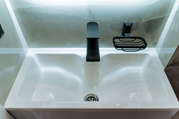 The elegantly designed bathroom boasts a contemporary sink accompanied by a chic black faucet and a coordinating soap dish, all combining to establish a sophisticated, modern aesthetic