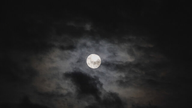Dark black clouds covering full moon in the sky, frightful scenery