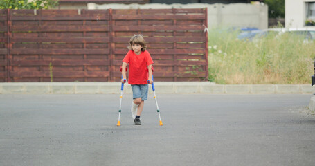 Boy with fractured leg in plaster cast, walking with medical orthopedic crutches