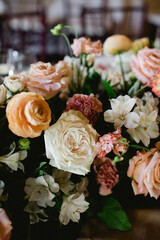 Flower arrangement with soft pastel roses and white blooms at an indoor event setting © tisaeff