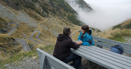 Young lovers couple rest on bench after hiking to the top of the mountain