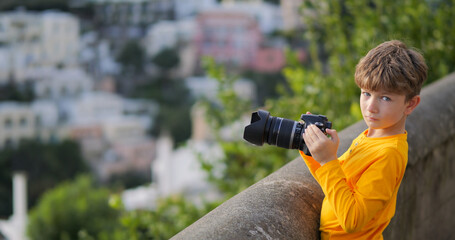 Fototapeta premium Cute boy with photo camera prepares to take pictures of Positano in Amalfi