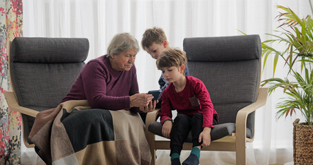 Grandmother showing something on mobile phone to the little kids
