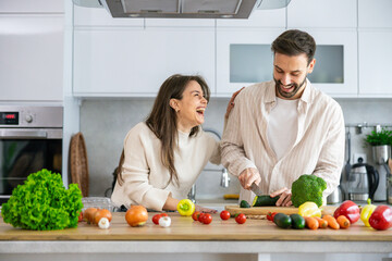 A joyful cooking session unfolds in a bright kitchen, showcasing a couple's playful interactions with fresh ingredients.